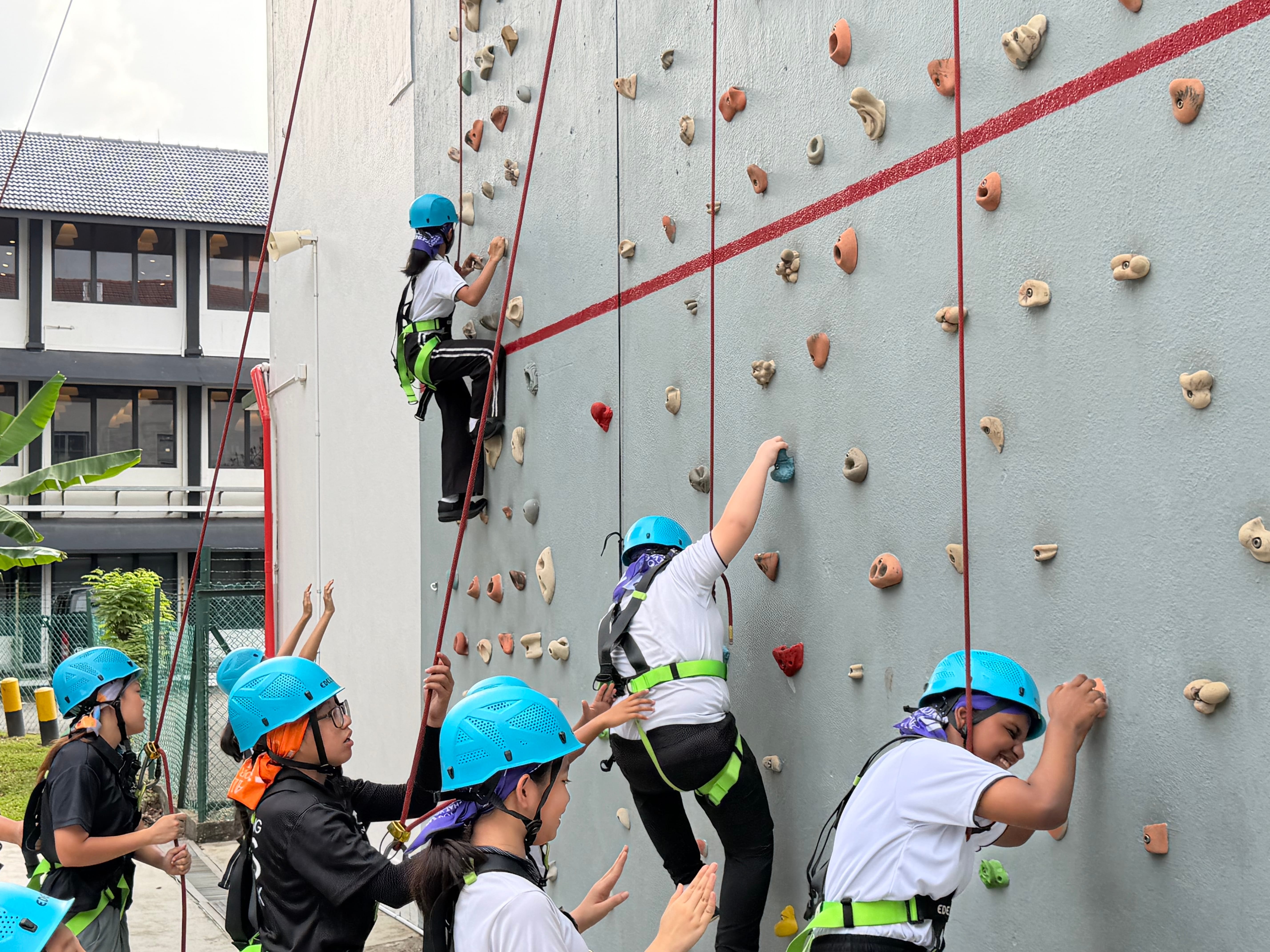 Cheered on by their friends, students take turns on the climbing wall.